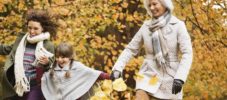 Three generations of women playing in autumn leaves